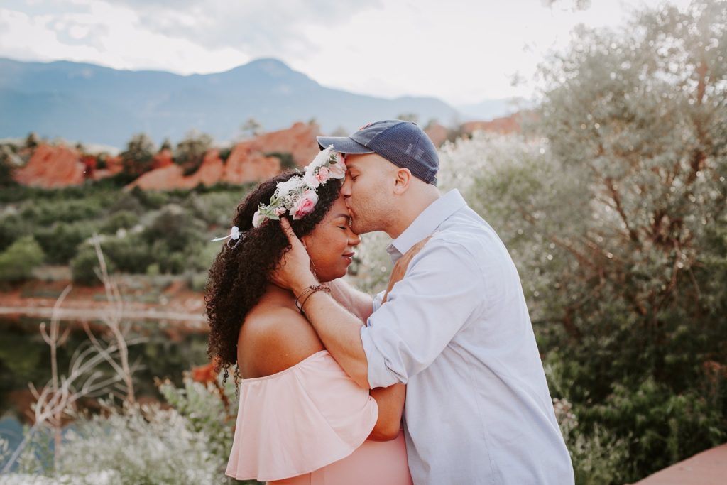 Husband kisses wife on forehead during golden hour maternity session 